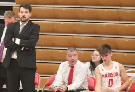 MCHS Head Basketball Coach Adam Stotts (black suit) surveys the court while Assistant Coach Kyle Tucker (red tie) looks on