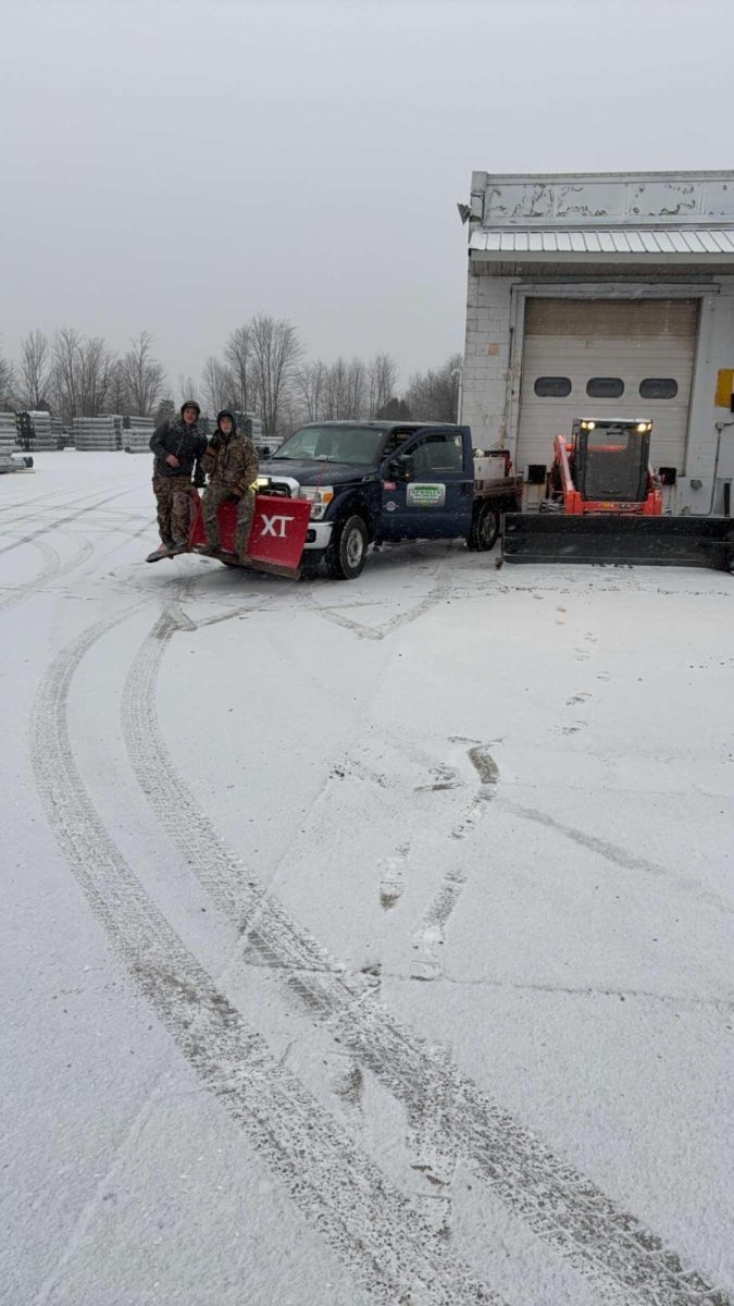 Current MCHS student Sawyer Felts poses on a snow plow with a fellow employee of Sproles Elite Lawn Care